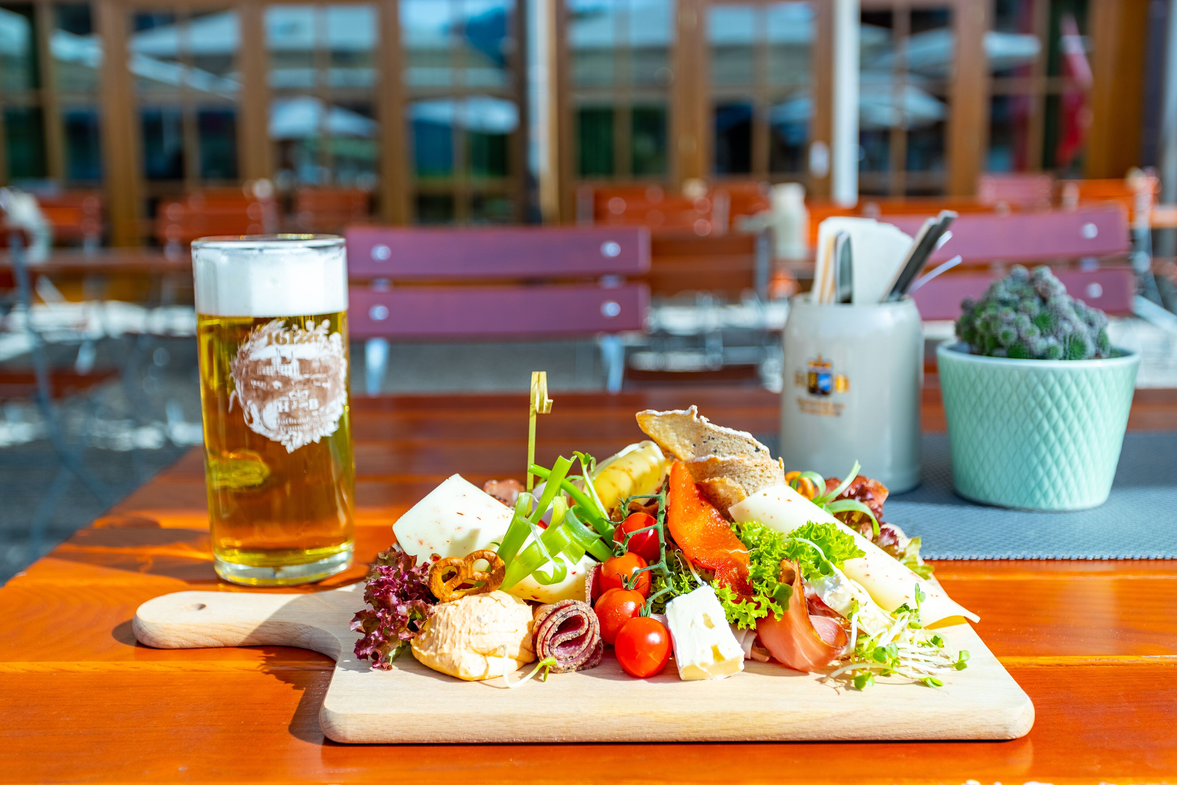A wooden table with a variety of food items and a glass of beer.