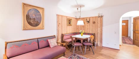 Una habitación acogedora con pared de madera, un sofá, una mesa de comedor con sillas y un ventilador de techo.