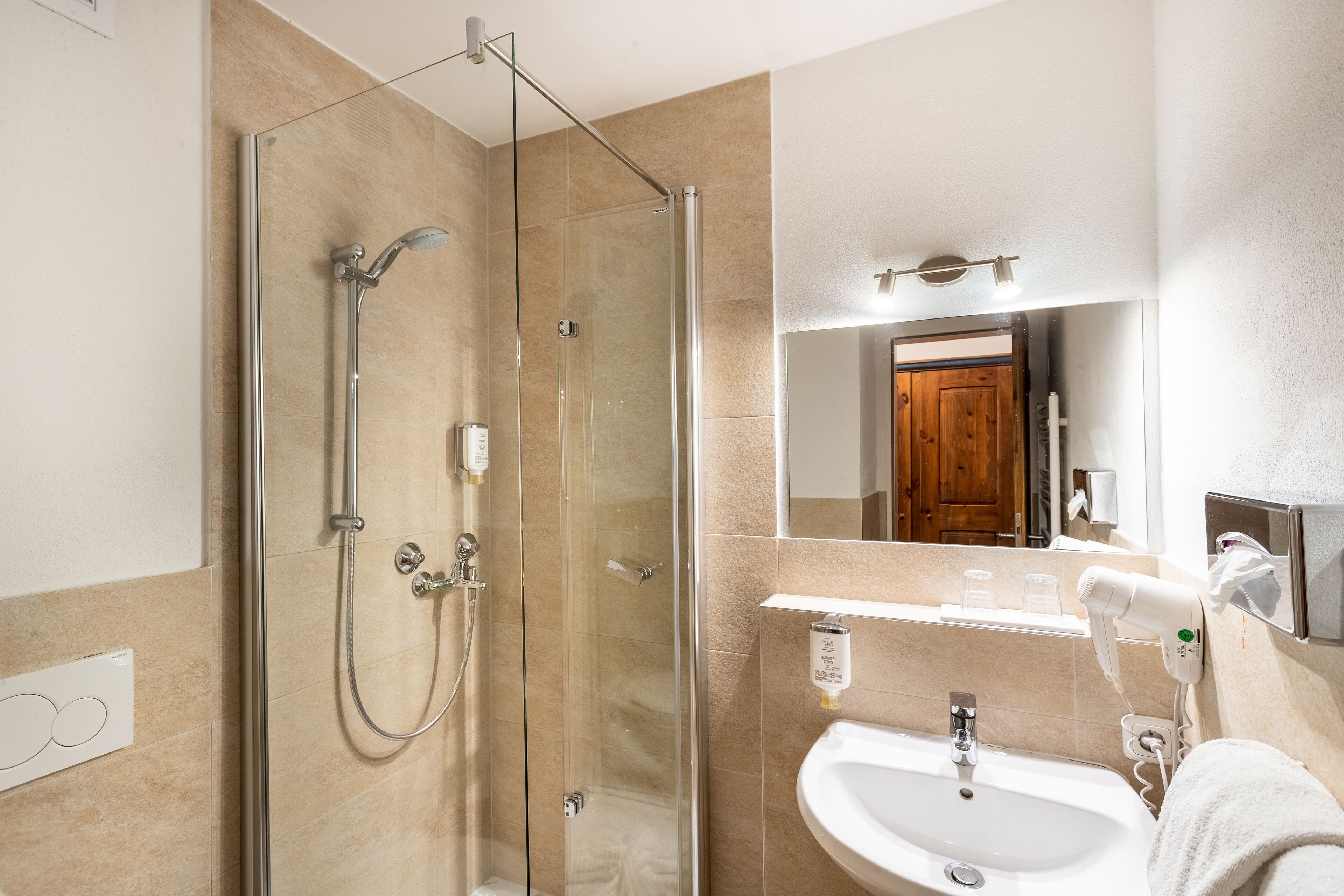 A modern bathroom with a glass-enclosed shower, a white sink, and a mirror above it.