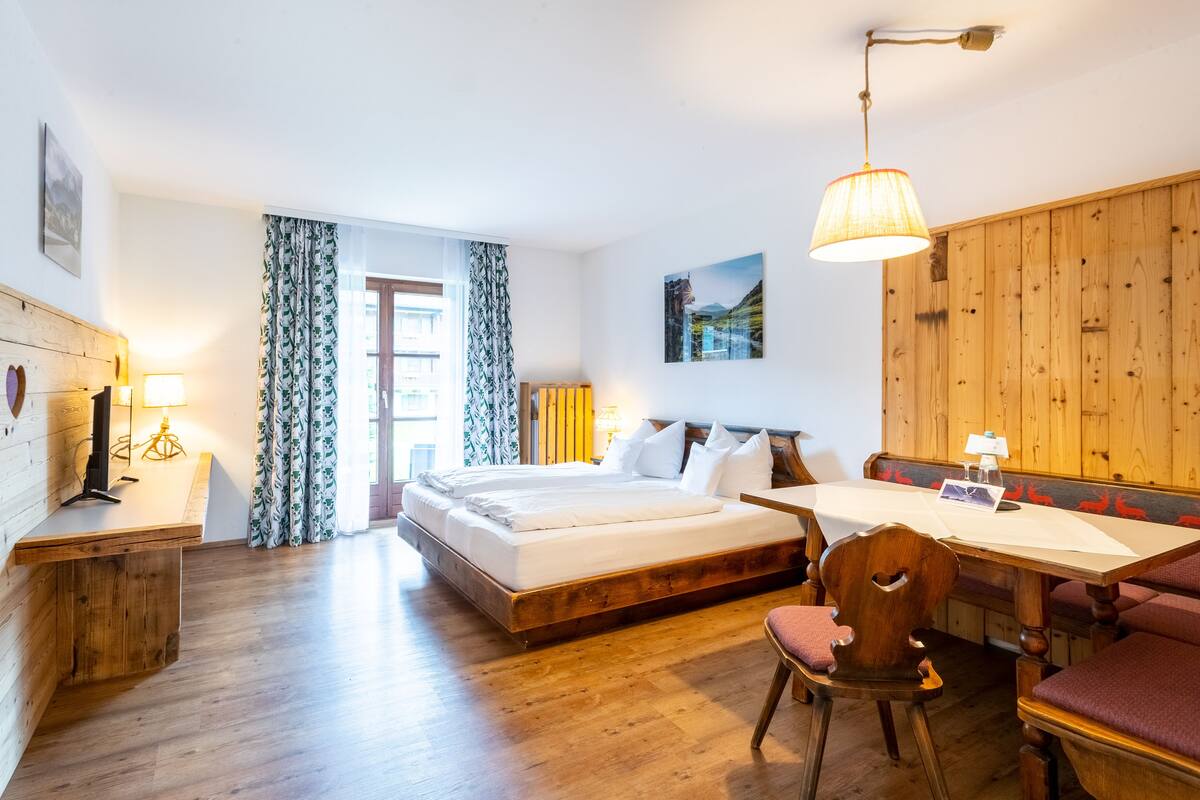 Une chambre à coucher avec un lit en bois, un bureau et un banc.