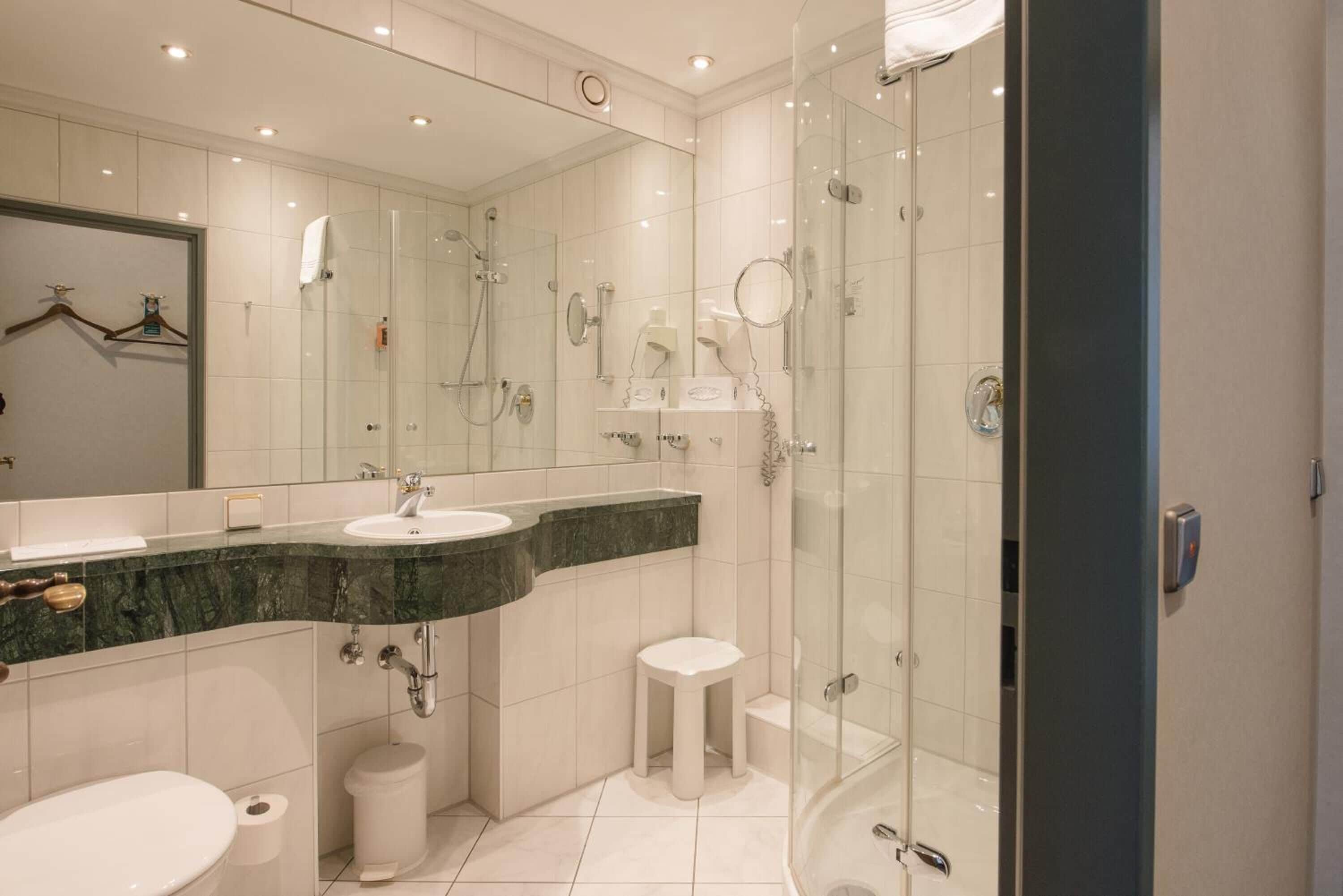 A modern bathroom with a glass-enclosed shower, a vanity with a marble countertop, and a large mirror.