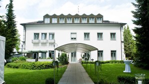 Ein großes, weißes Gebäude mit einem überdachten Gang, der zu einer Tür führt.