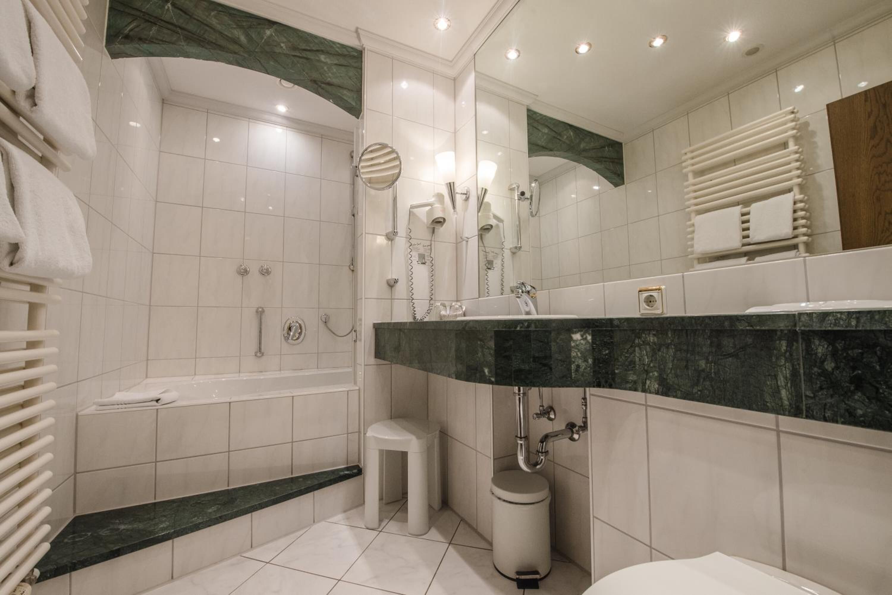 Un baño moderno con bañera, tocador de mármol, inodoro y zona de ducha.