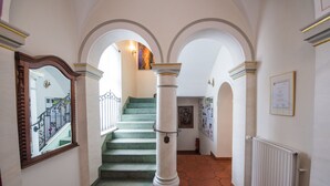 Eine Treppe mit grünem Teppich, weißen Säulen und einem gefliesten Boden.