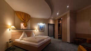 Ein Hotelzimmer mit zwei Betten, einem Schreibtisch, einem Stuhl, einem Kleiderschrank und einem Bild an der Wand.