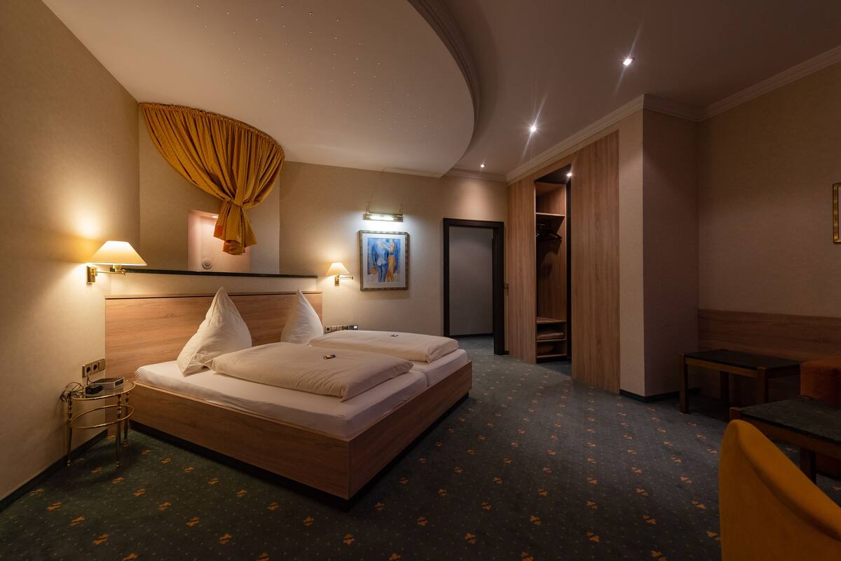 Een hotelkamer met twee bedden, een bureau, een stoel, een kledingkast en een schilderij aan de muur.