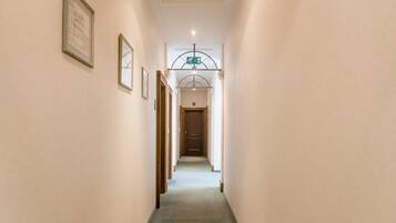 A narrow hallway with a carpeted floor, framed pictures on the walls, and a door at the end.