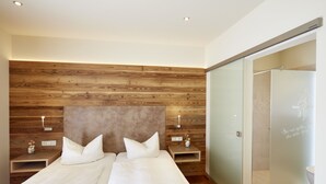 A bedroom with a wooden headboard, two bedside tables with lamps, and a sliding door to the bathroom. - Landgasthof Fiedler (Dietersheim)