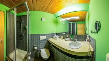 A bathroom with a shower, toilet, sink, and mirror.