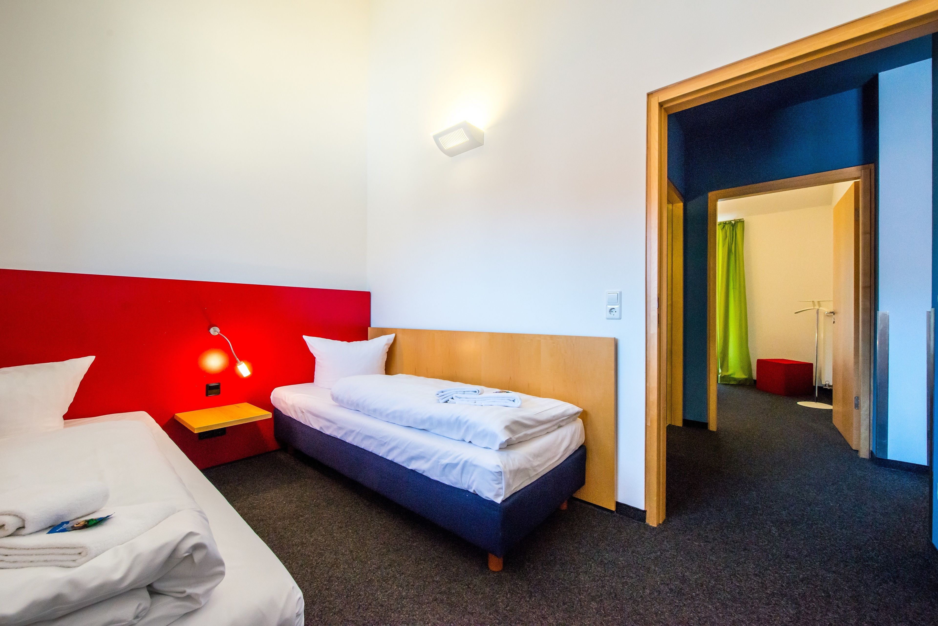 A hotel room with a bed, a nightstand with a lamp, and a wooden headboard.