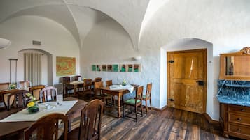 A dining area with wooden tables and chairs, a wooden cabinet, and a large wooden door.