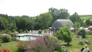 Ein Garten mit Swimmingpool, Liegestühlen und einer Steinstruktur.