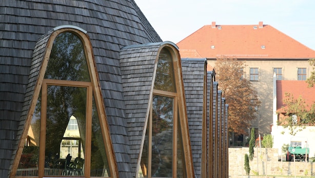 Ein Gebäude mit großen Bogenfenstern und einem geneigten Dach.