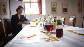 Ein Konferenzraum mit einem langen Tisch, verschiedenen Getränken und einer Person, die ein Dokument liest.