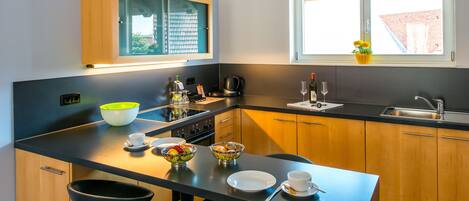 A modern kitchen with a central island, wooden cabinets, and a window with a view of the outside.