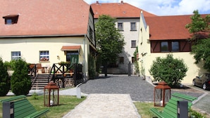 Ein Innenhof mit einem Steinweg, Bänken und einem Gebäude mit roten Ziegeldach.