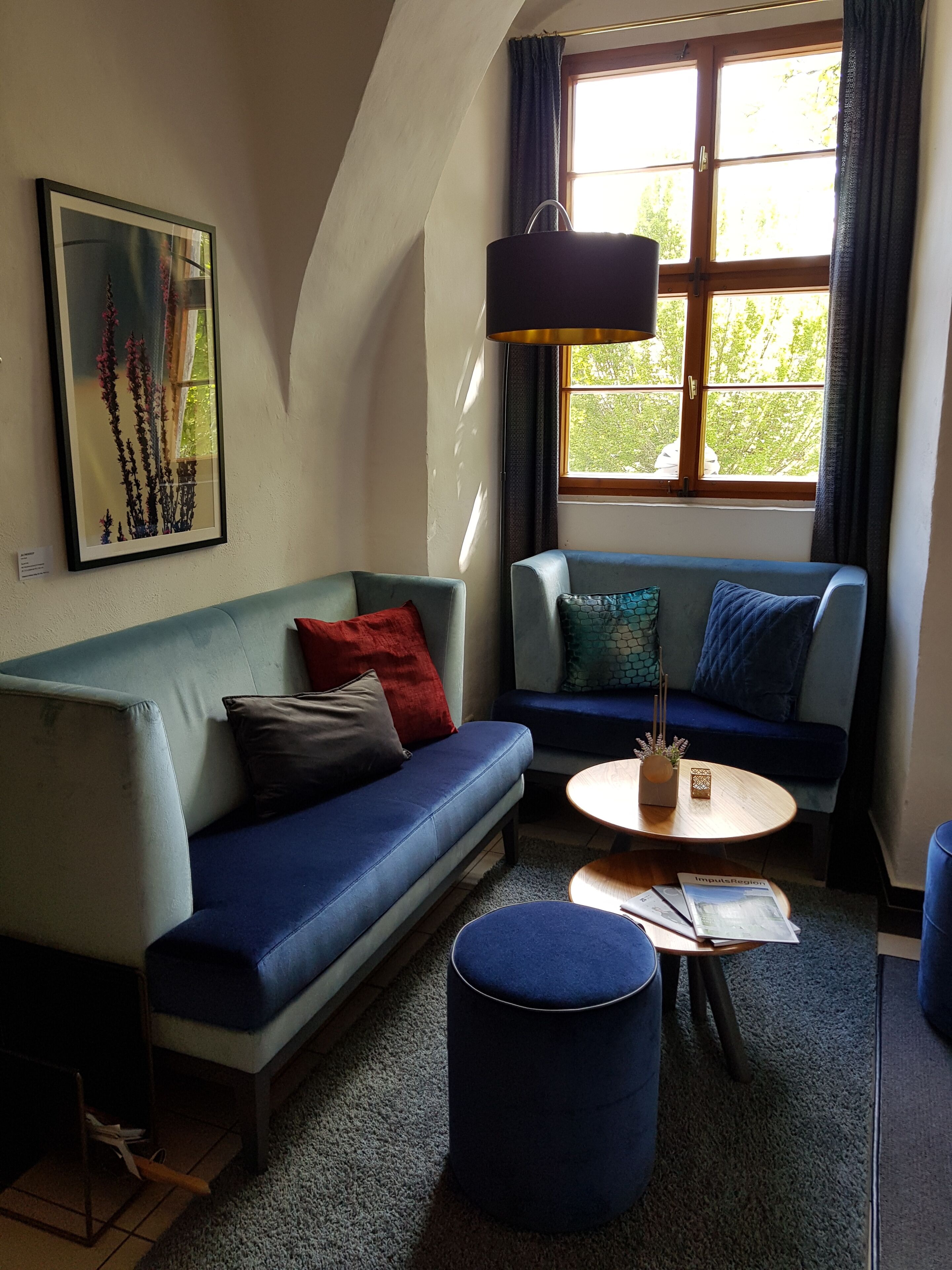 Een gezellige woonkamer met een blauwe bank, een ronde salontafel en een klein voetenbankje.
