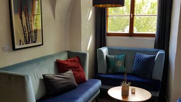 Een gezellige woonkamer met een blauwe bank, een ronde salontafel en een klein voetenbankje.