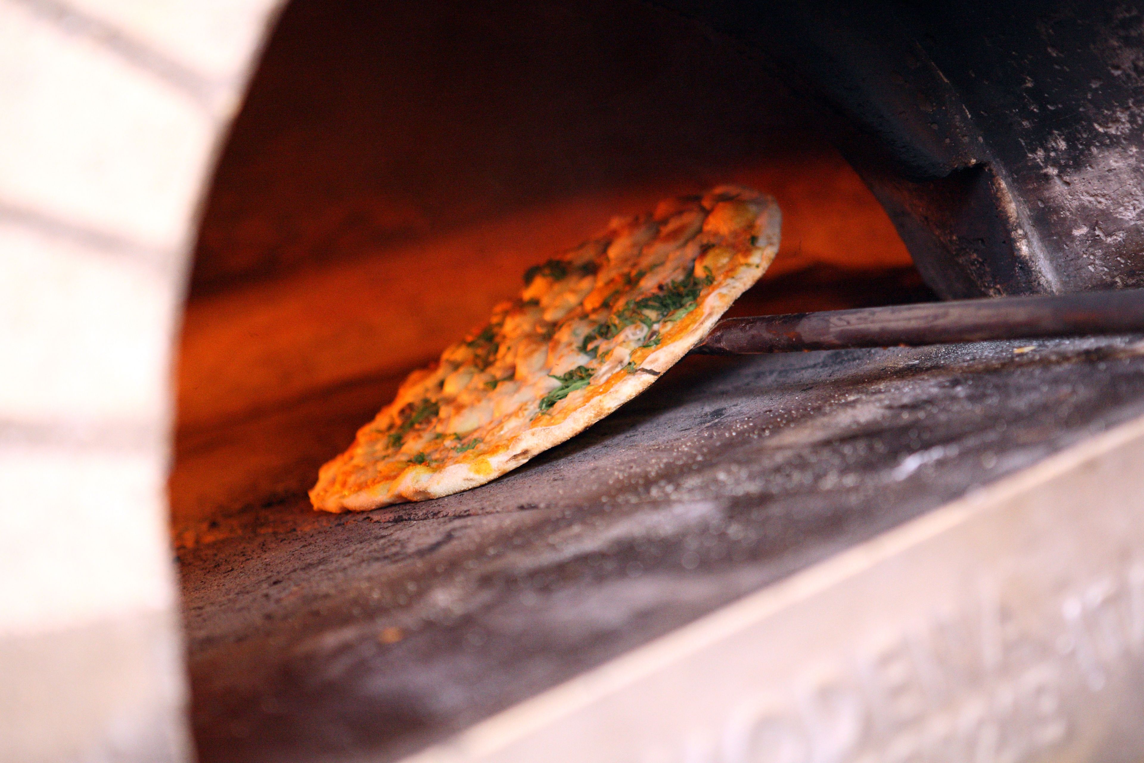 Eine Pizza in einem Backofen aus Ziegelsteinen.