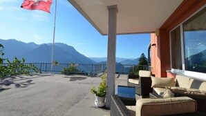 A balcony with a view of mountains, a flag, and outdoor furniture. - Hotel Alvier (Wartau)