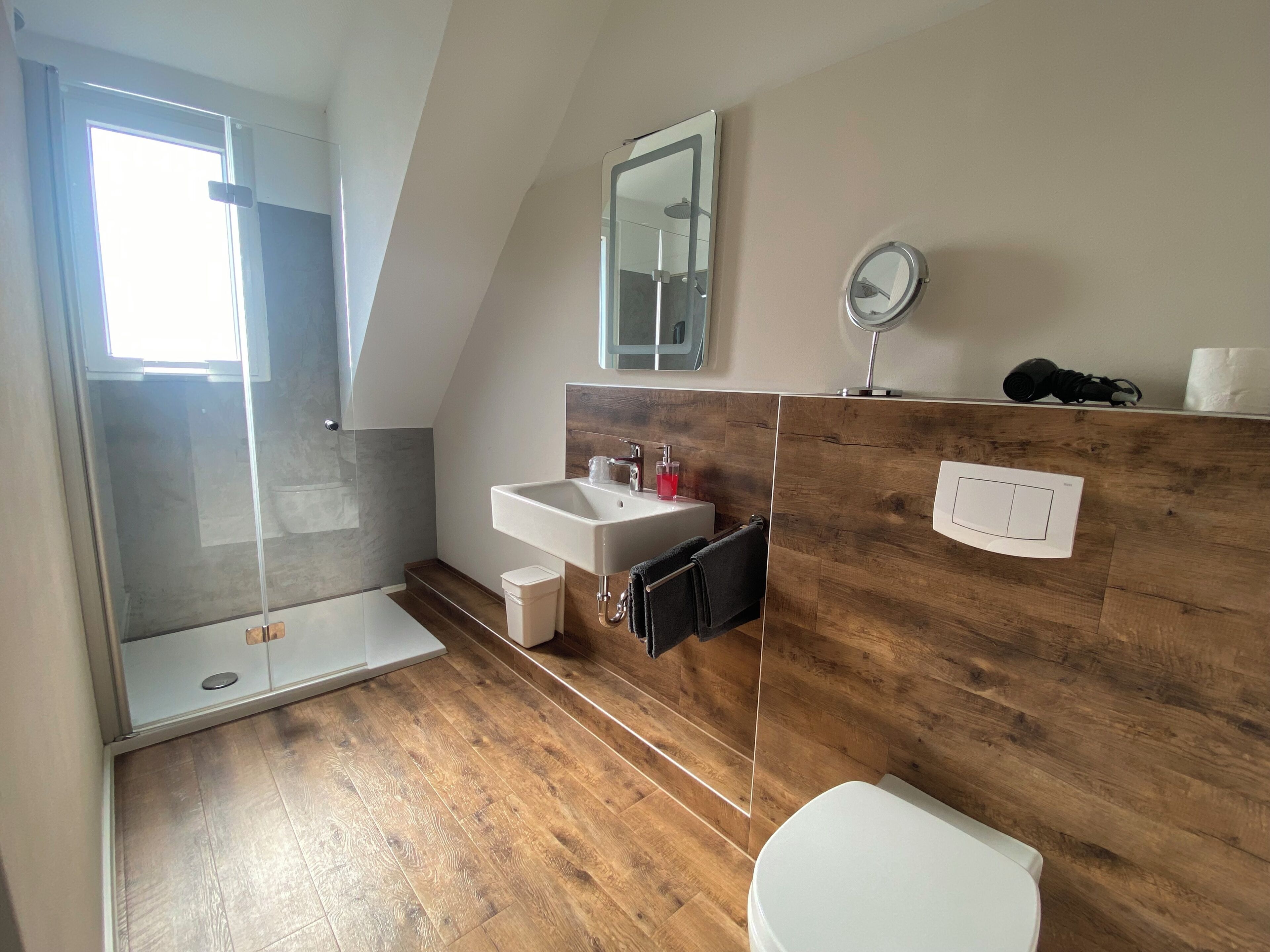 A modern bathroom with a shower, sink, and toilet.