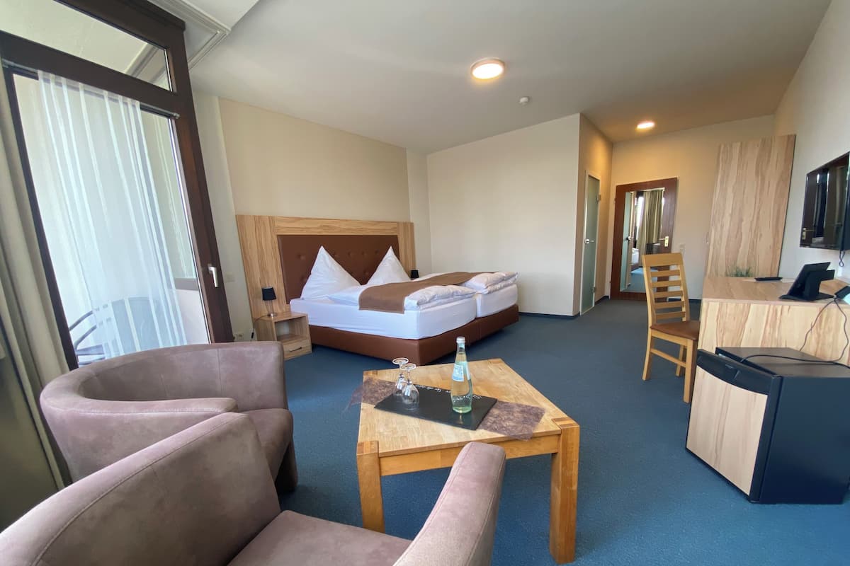 A hotel room with a bed, a desk, a chair, and a sofa.