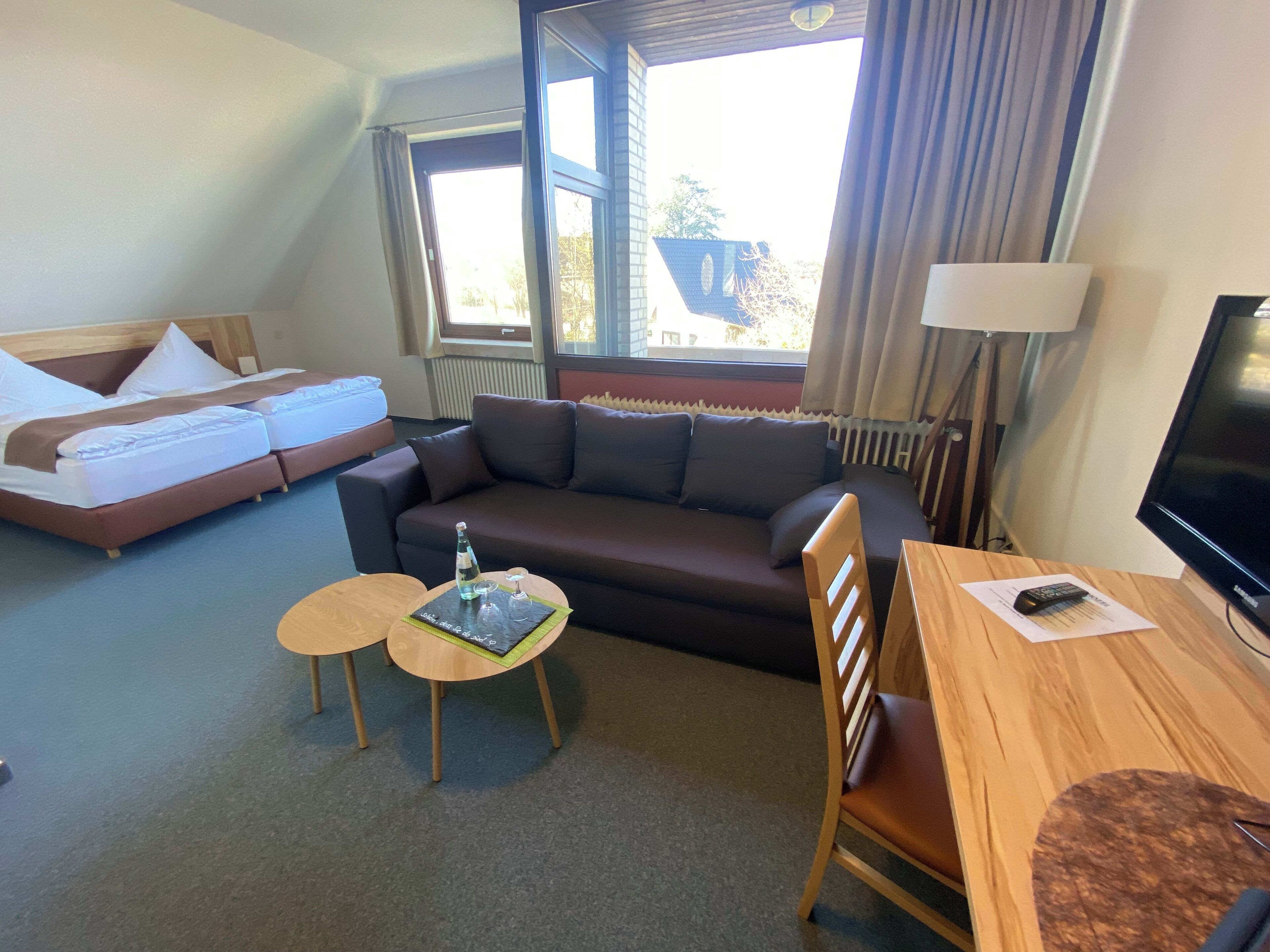 Ein Hotelzimmer mit Bett, Sofa, Esstisch und Fernseher.