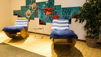 Relax in a serene space with two comfortable chairs, a potted plant, and a unique wall mural.