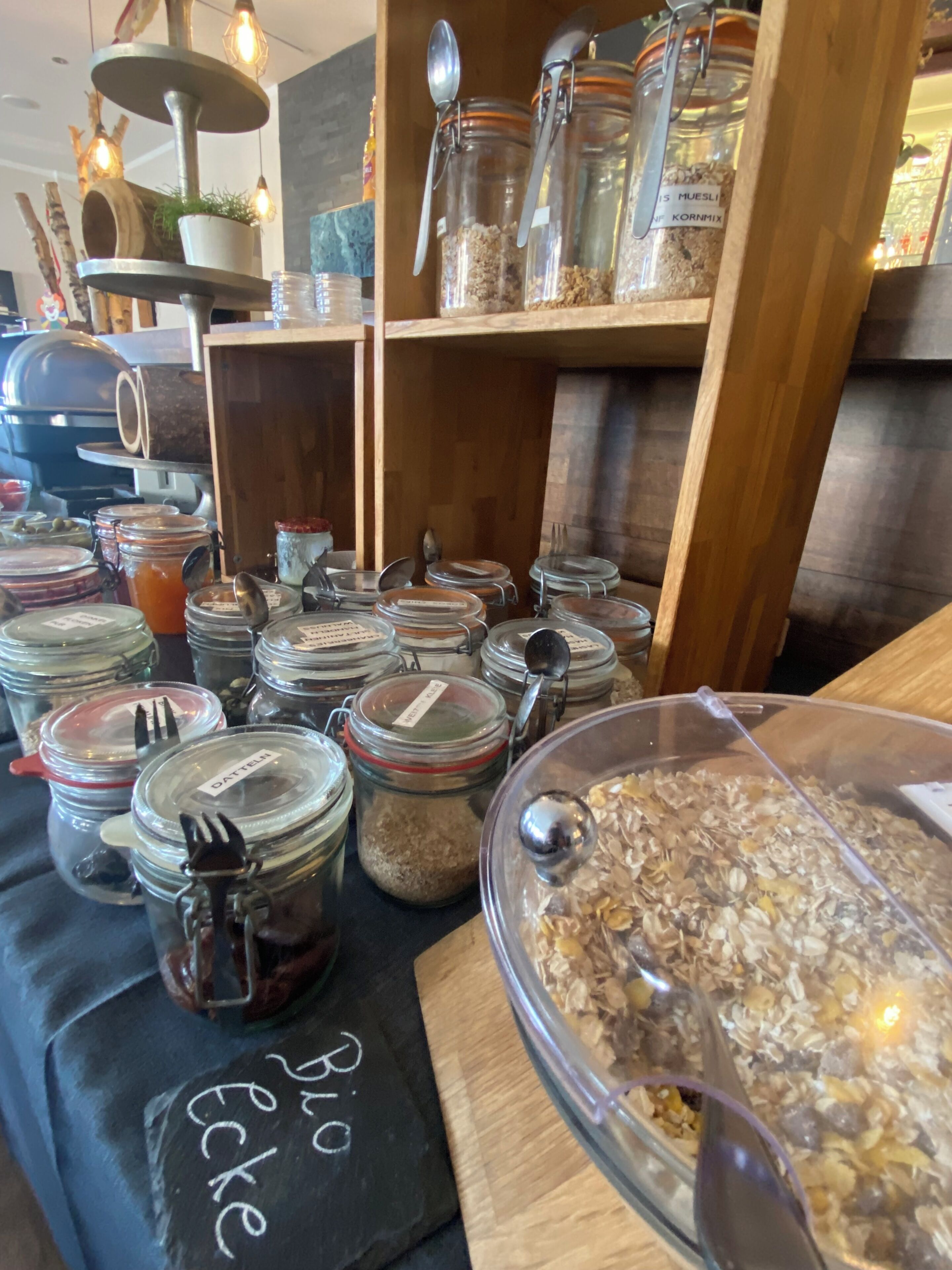 A buffet area with multiple glass jars containing various food items, each with a metal spoon and fork.