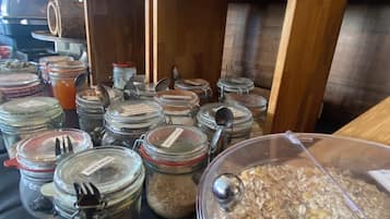 A buffet area with multiple glass jars containing various food items, each with a metal spoon and fork.