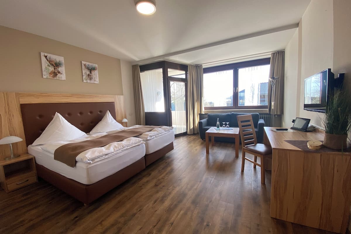 A hotel room with a bed, bedside tables, a desk with a chair, a TV, and a large window.