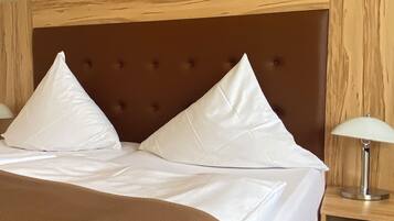A bed with white linens, two pillows, and a brown headboard in a hotel room.