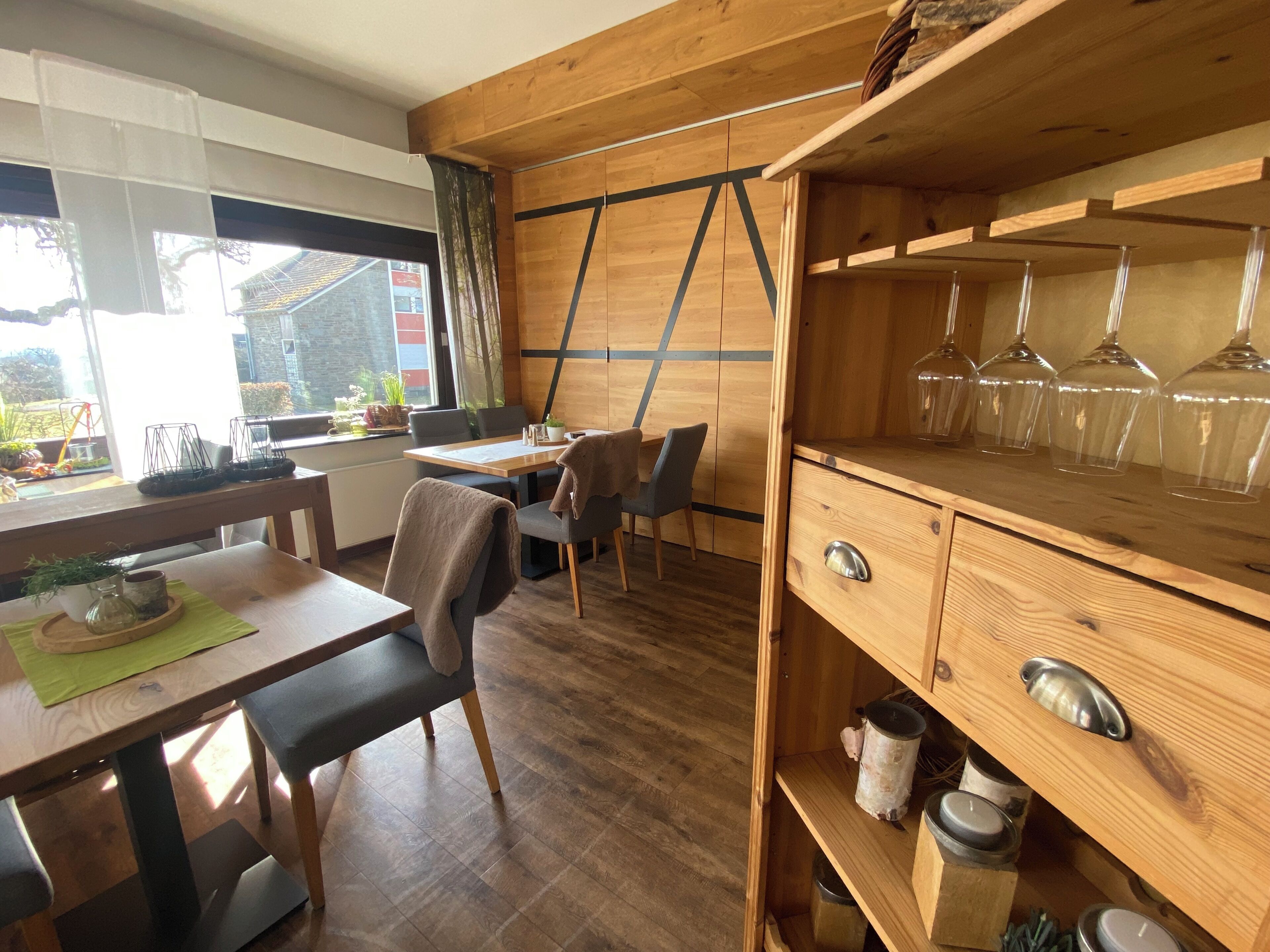 Un interior de madera con comedor, sillas, una mesa y una repisa con velas.