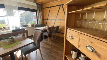Un interior de madera con comedor, sillas, una mesa y una repisa con velas.