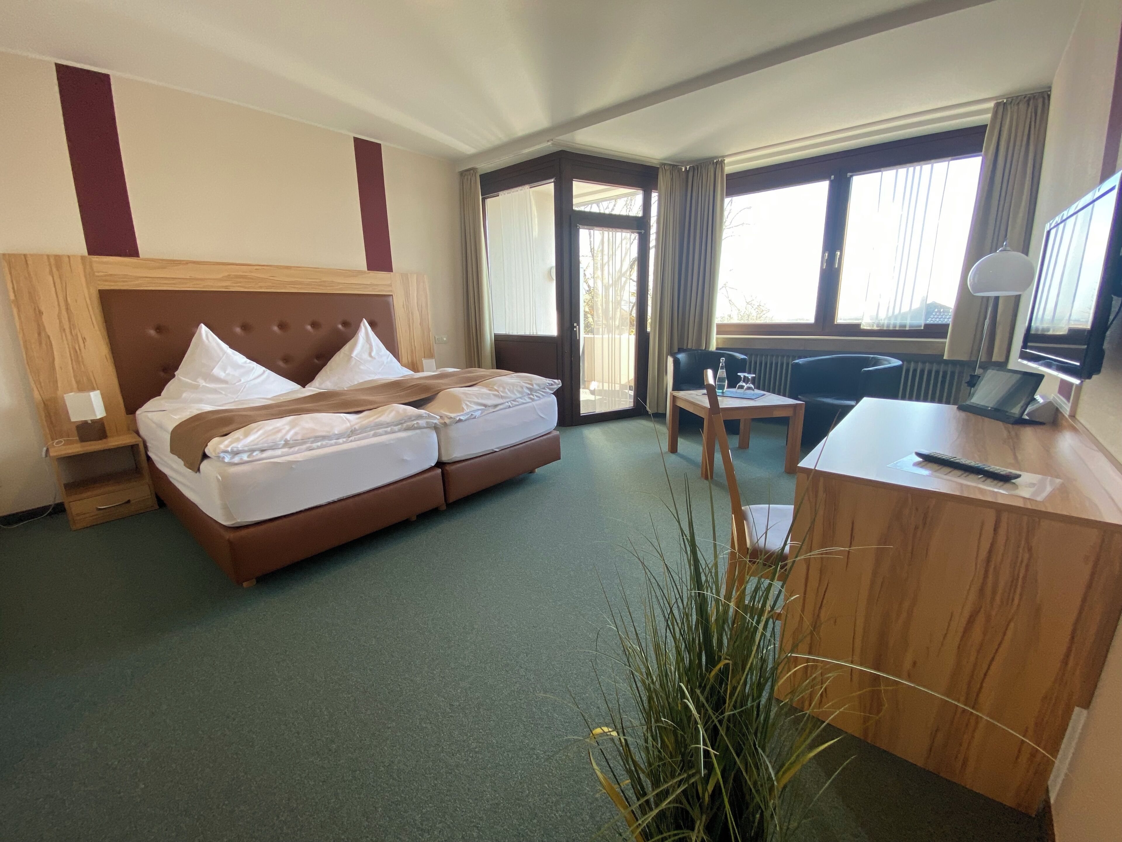 Ein Hotelzimmer mit Bett, Schreibtisch, Stuhl und Blick durch das Fenster.