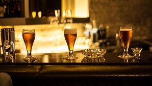 Un bar con tres vasos de cerveza sobre una barra.