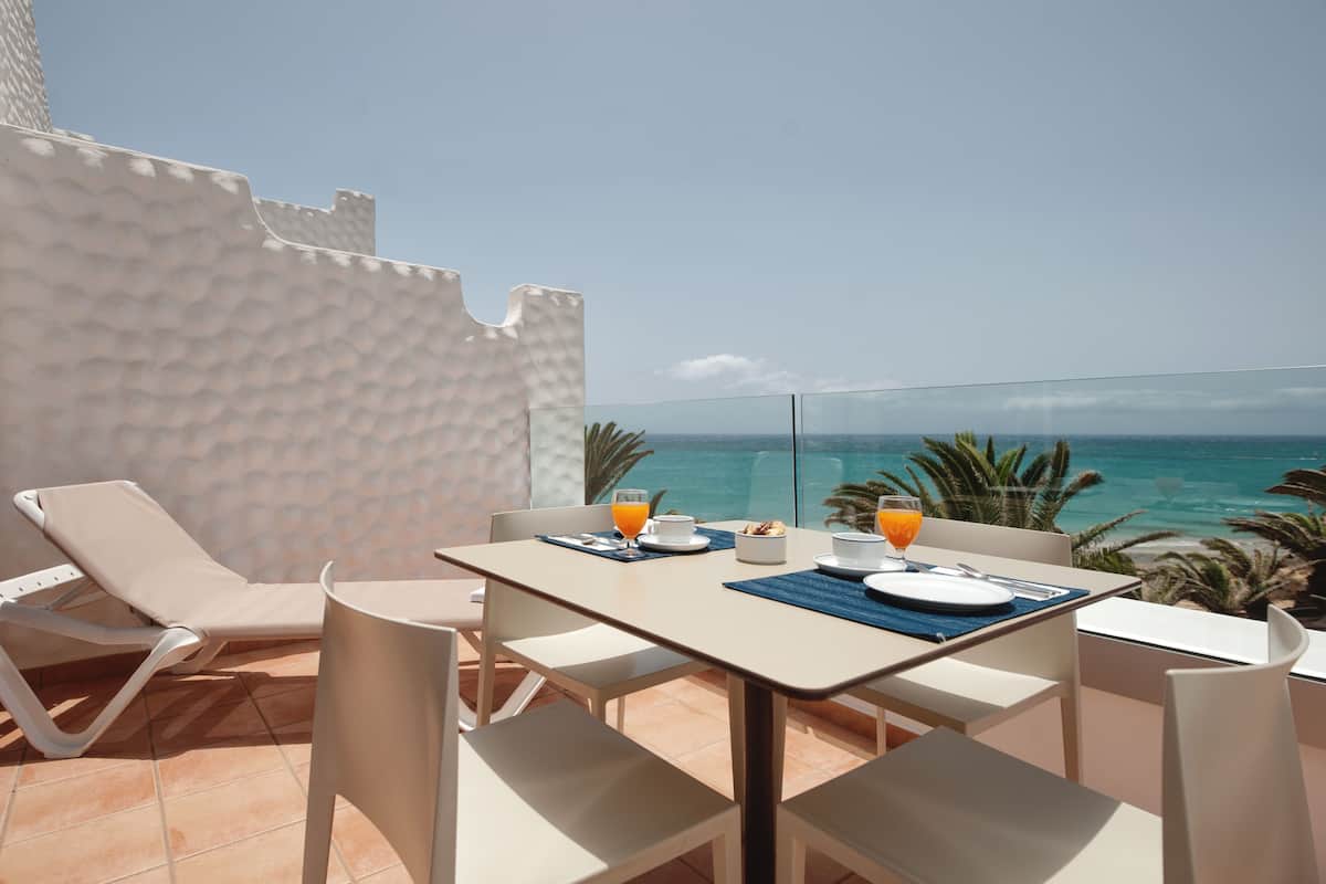 Un balcón con una mesa lista para el desayuno, con vistas al mar.