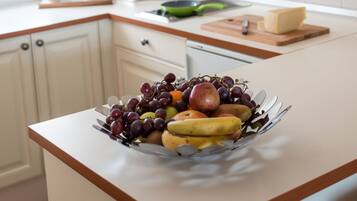 Una cocina con armarios blancos, un frutero en la encimera y una ventana con luz natural.