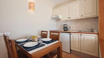 Cocina compacta con una mesa de comedor preparada para dos personas, cafetera y lavavajillas.