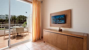 Una camera moderna con una porta in vetro che dà su un balcone, un armadio in legno e un televisore a schermo piatto montato a parete.