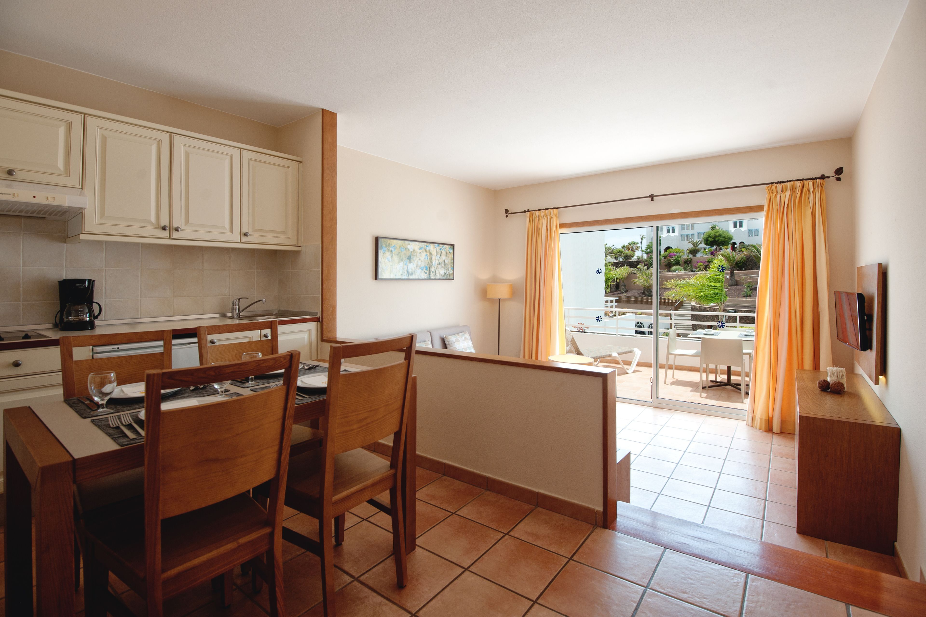 Una cocina compacta con zona de comedor, televisión y vistas al exterior.