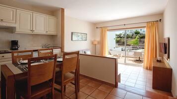 Una cocina compacta con zona de comedor, televisión y vistas al exterior.