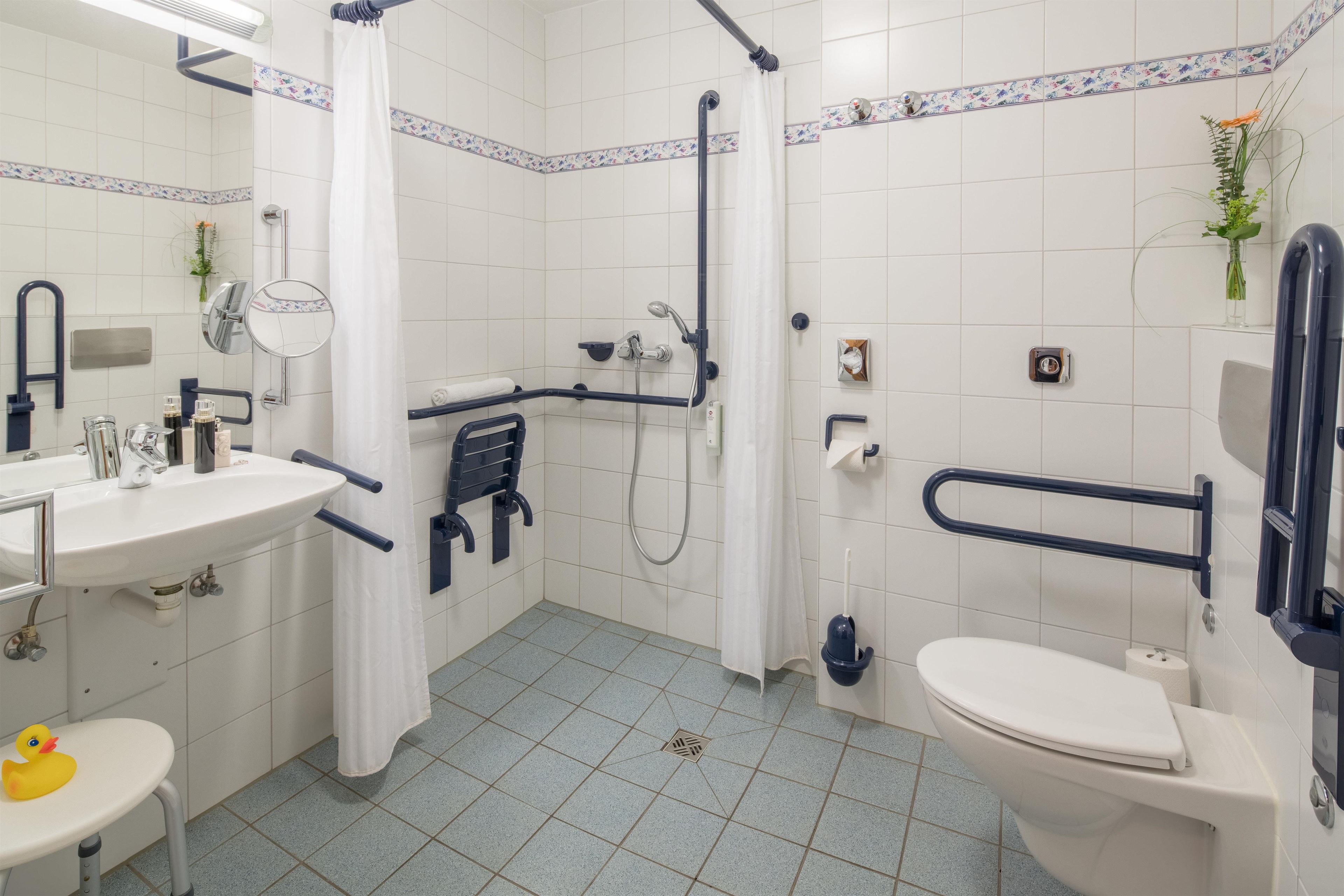 A bathroom with a white sink, toilet, and shower area.