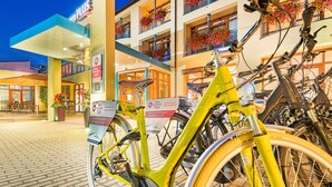 Un hôtel avec une enseigne indiquant « Best Western PLUS » et un vélo jaune garé devant.
