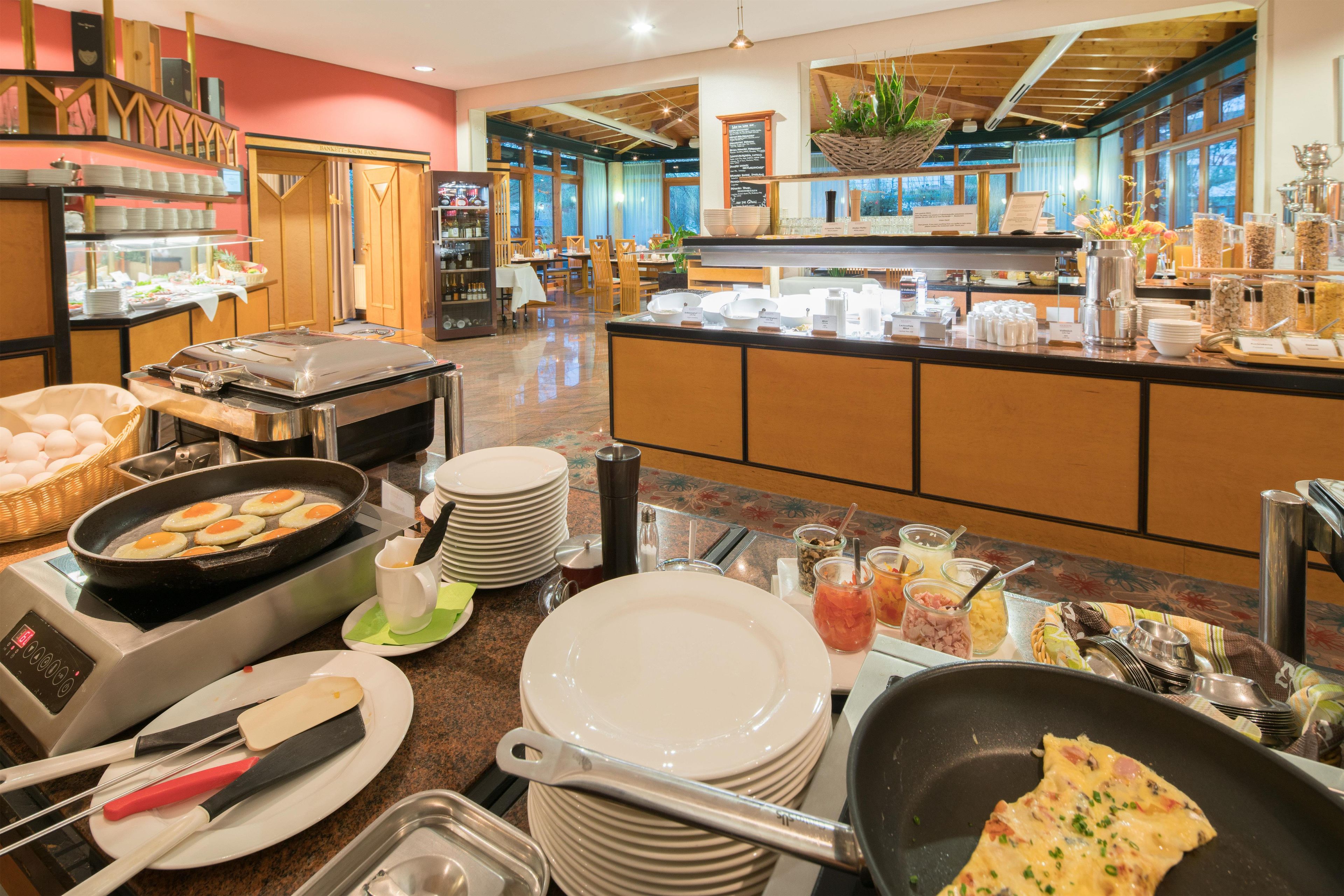 Zona de buffet con diferentes opciones de comida, una estación de café y un área de estar con mesas y sillas.