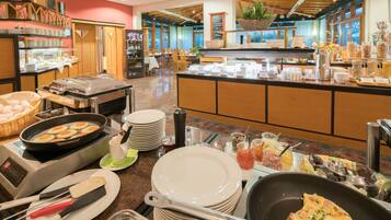 Zona de buffet con diferentes opciones de comida, una estación de café y un área de estar con mesas y sillas.