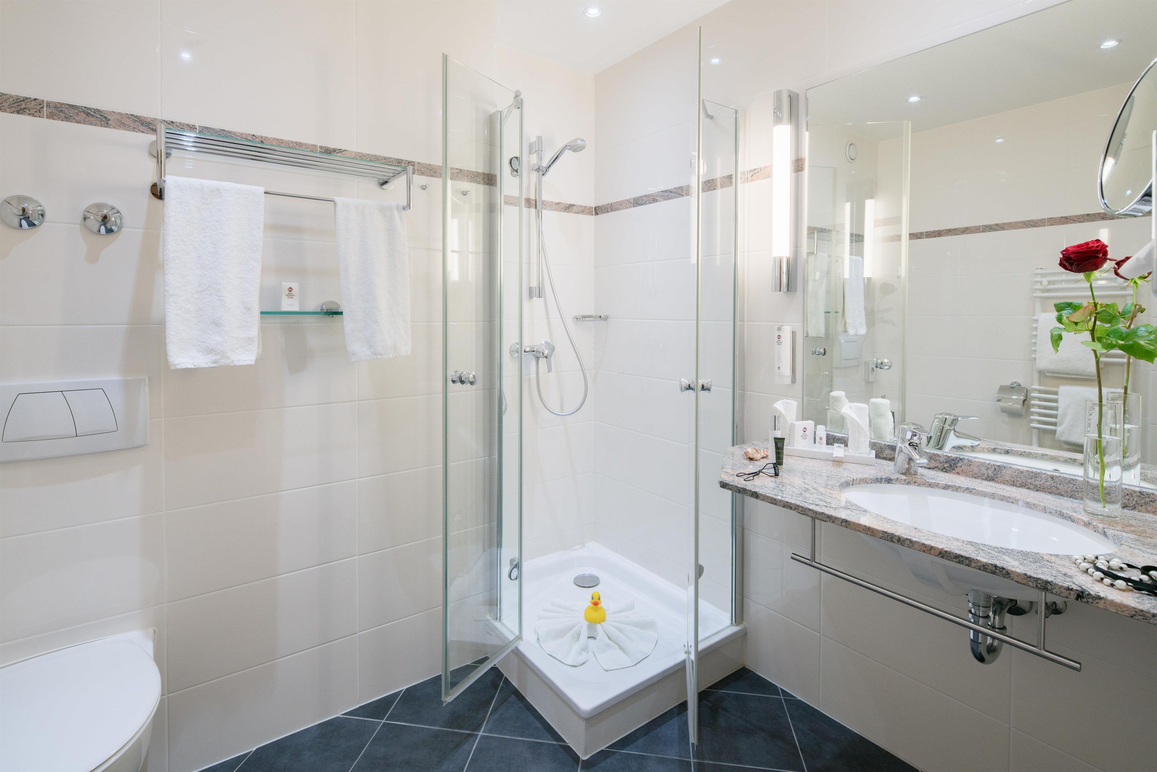 Une salle de bain moderne avec une douche à parois de verre, une baignoire blanche et un meuble-lavabo doté d’un grand miroir.