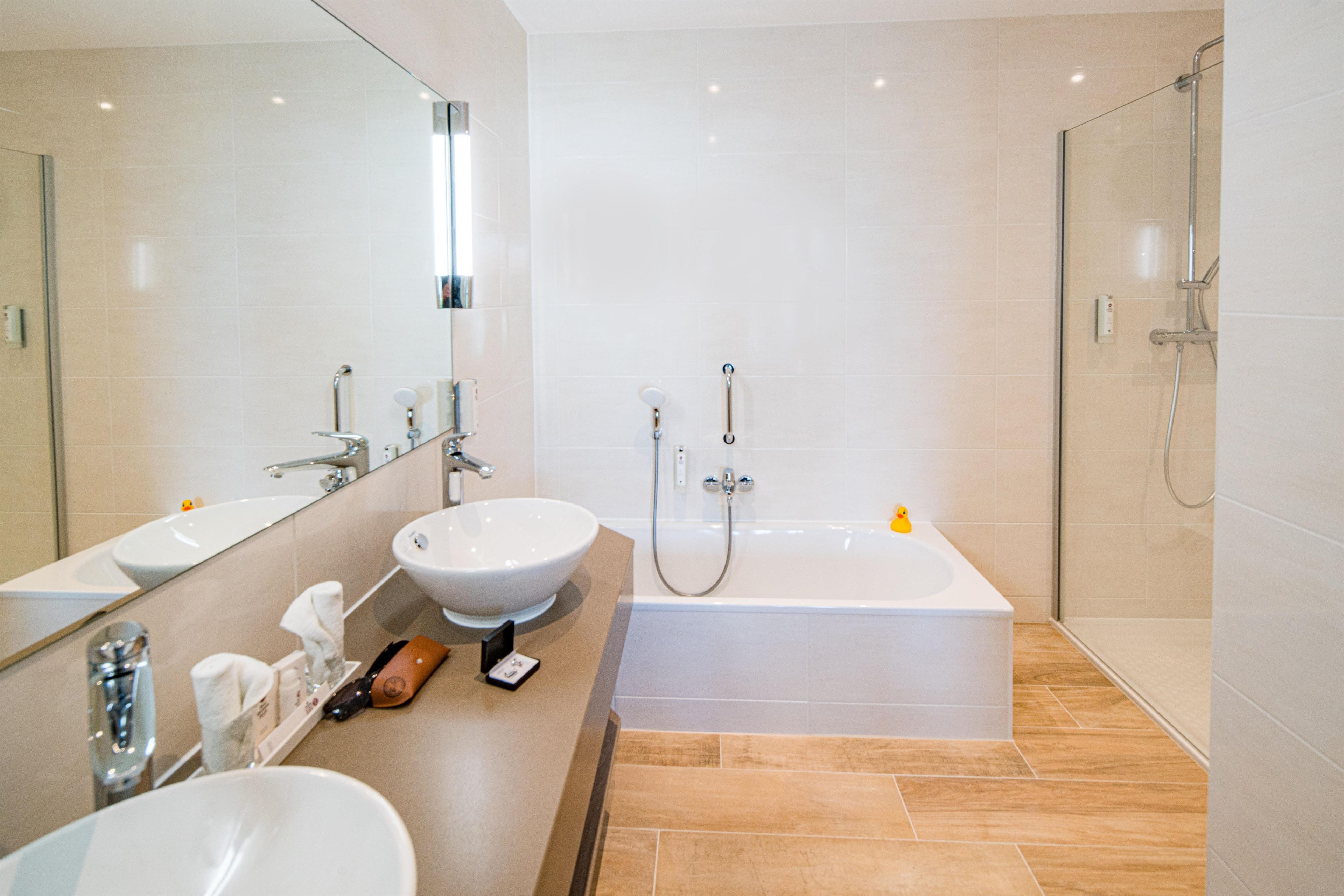 Un baño moderno con un espejo grande, un lavabo, una bañera y una ducha.