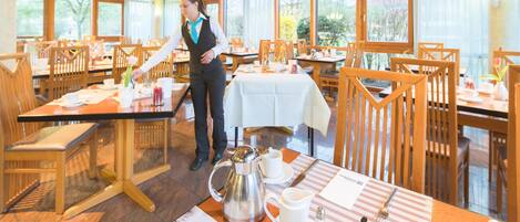 A restaurant with wooden furniture, a waiter, and a menu on the table.