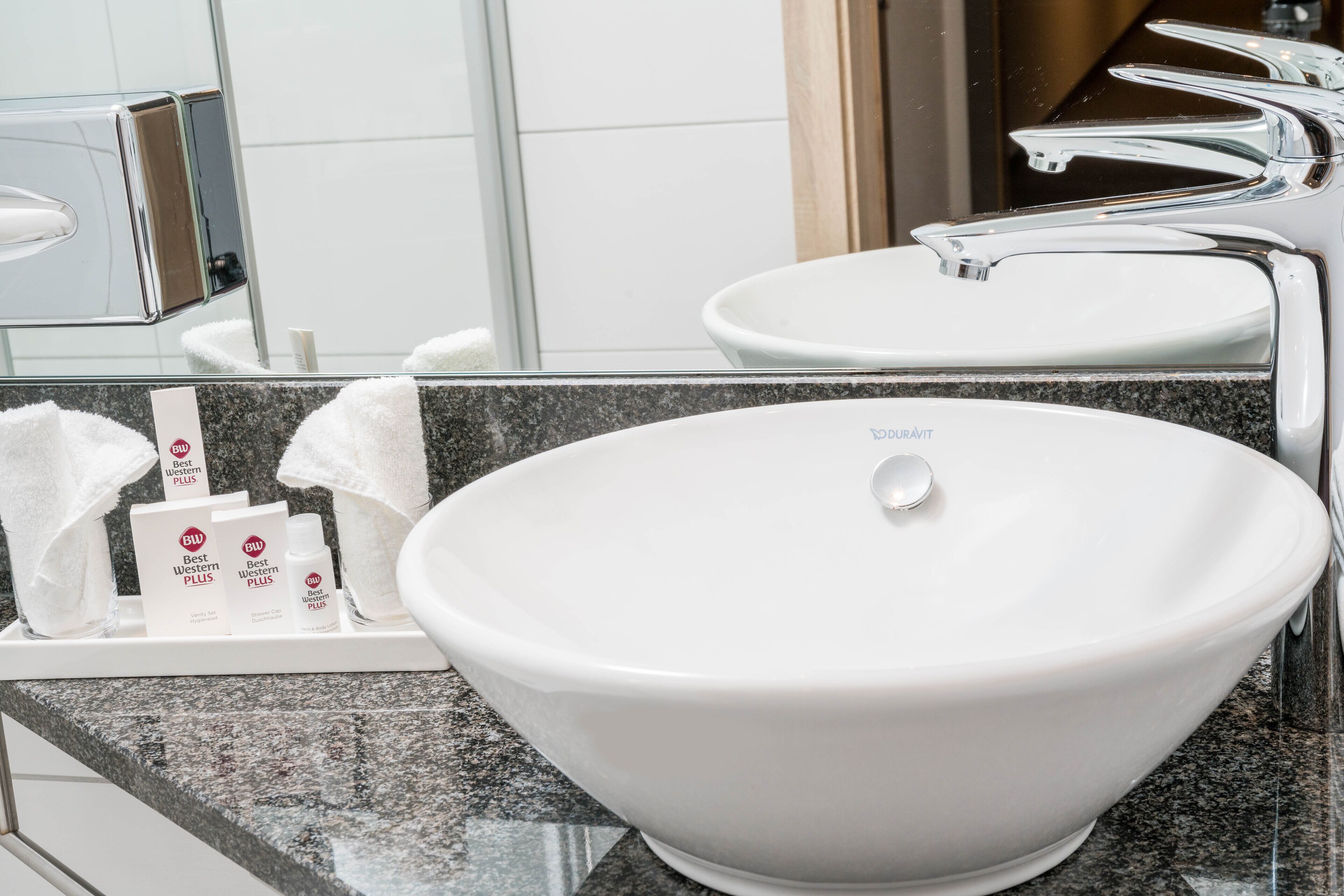 Une salle de bain avec un grand lavabo sur pied blanc, un miroir et un plateau contenant des articles de toilette.